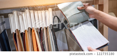 Designer hand choosing fabric pieces from fabric swatch material Designer hand choosing fabric pieces from fabric swatch material 122735180