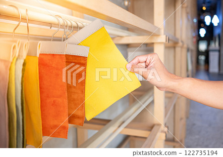Stylist hand choosing yellow fabric piece from fabric swatch material. Upholstery sample collection Stylist hand choosing yellow fabric piece from fabric swatch material. Upholstery sample collection 122735194