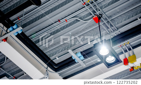 Spotlight lamp hanging under electrical cable conduit wiring with junction box and plumbing pipeline Spotlight lamp hanging under electrical cable conduit wiring with junction box and plumbing pipeline 122735202
