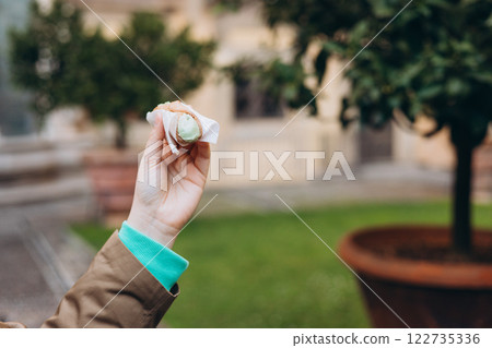 Woman holding Sicilian cannolo tube pastry filled with cream outdoors. Travel, Italy, food and holidays concept. Girl eating traditional delicious cake cannoli, Traveling Europe 122735336