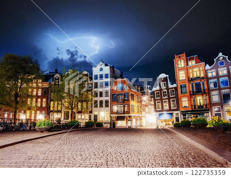 Amsterdam canal at beautiful cumulus clouds and lightning. The city is the capital and most populous city in the Netherlands. 122735359