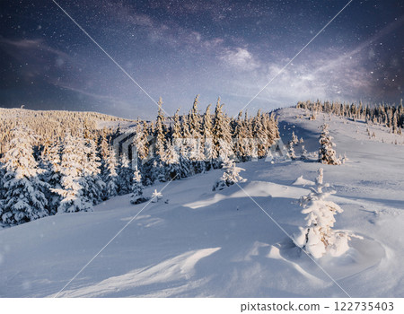 starry sky in winter snowy night. fantastic milky way in the New Year's Eve. Starry sky snowy winter night. The Milky Way is a fantastic New Year's Eve. Winter road in the mountains 122735403