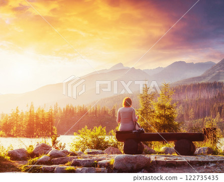 Lake Strbske pleso in High Tatras mountain, Slovakia, Europe. The girl sits on a bench and looks into the fairy-tale sky 122735435