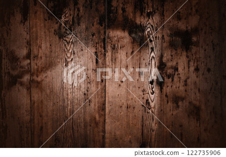 A close up of very old wooden planks with a dark, aged, and weathered texture. The rough surface features deep cracks, visible knots, and a natural distressed look, adding a vintage and rustic charm. A close up of very old wooden planks with a dark, aged, and weathered texture. The rough surface features deep cracks, visible knots, and a natural distressed look, adding a vintage and rustic charm. 122735906