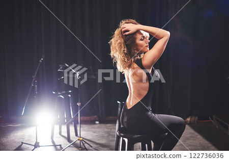 Young sexy woman in black sitting on chair. Retro style film colors effect Young sexy woman in black sitting on chair. Retro style film colors effect 122736036