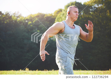 Fitness man athlete jogging in the nature during sunset. Person running working out living an active lifestyle training cardio in summer in sportswear and shoes. 122736294