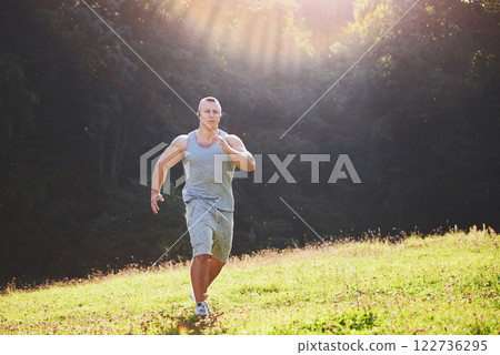 Fitness man athlete jogging in the nature during sunset. Person running working out living an active lifestyle training cardio in summer in sportswear and shoes. 122736295