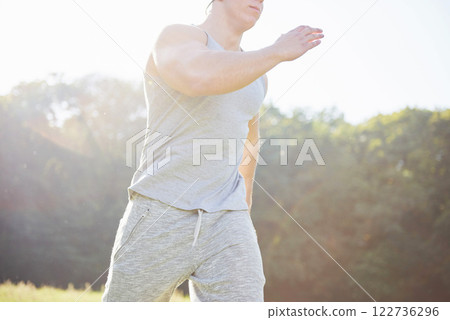 Fitness man athlete jogging in the nature during sunset. Person running working out living an active lifestyle training cardio in summer in sportswear and shoes. 122736296