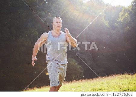 Fitness man athlete jogging in the nature during sunset. Person running working out living an active lifestyle training cardio in summer in sportswear and shoes. Fitness man athlete jogging in the nature during sunset. Person running working out living an active lifestyle training cardio in summer in sportswear and shoes. 122736302