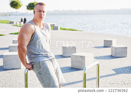 Young male jogger athlete training and doing workout outdoors in city 122736362