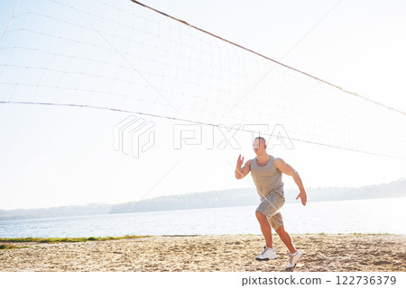 A athletic man looking at the seaside on the wild sand beach. Masculine and sporty male with naked torso is doing evening training at the sea cost. Summer work-out training outdoors 122736379