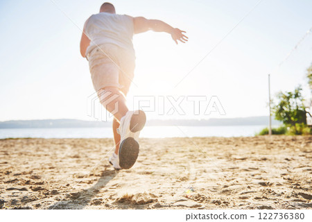 Outdoor cross-country running in summer sunshine concept for exercising, fitness and healthy lifestyle. Close up of feet of a man running in grass 122736380