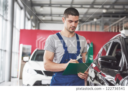 Portrait of a mechanic at work in his garage - car service, repair, maintenance and people concept 122736541