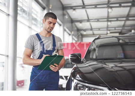 Portrait of a mechanic at work in his garage - car service, repair, maintenance and people concept 122736543