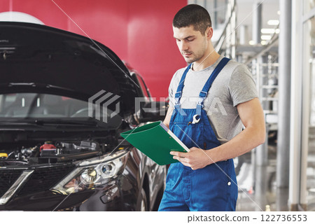 car service, repair, maintenance and people concept - auto mechanic man or smith with clipboard at workshop car service, repair, maintenance and people concept - auto mechanic man or smith with clipboard at workshop 122736553