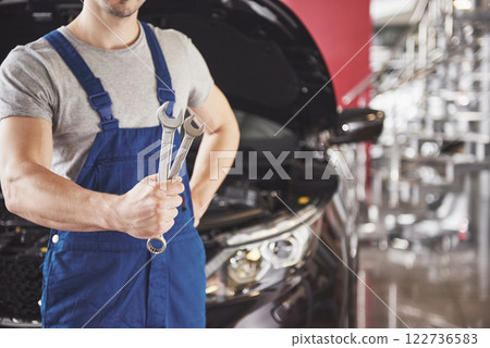 Hands of car mechanic with wrench in garage 122736583