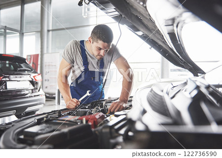 Picture showing muscular car service worker repairing vehicle 122736590