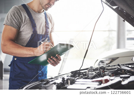 Portrait of a mechanic at work in his garage - car service, repair, maintenance and people concept Portrait of a mechanic at work in his garage - car service, repair, maintenance and people concept 122736601