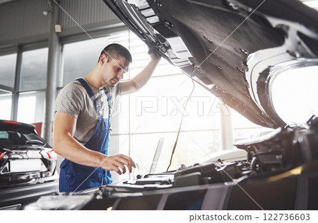 Picture showing muscular car service worker repairing vehicle Picture showing muscular car service worker repairing vehicle 122736603