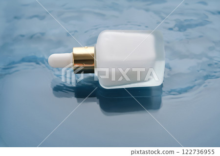 Bottle with white moisturizing serum in water on blue background. Bottle with white moisturizing serum in water on blue background. 122736955