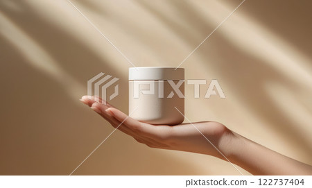 hand presents matte ceramic cosmetic jar against subtle beige backdrop, showcasing minimalist elegance 122737404