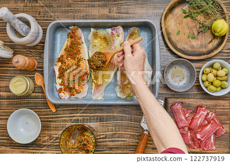 Freshly prepared fish fillets with herbs and spices on a wooden kitchen table 122737919