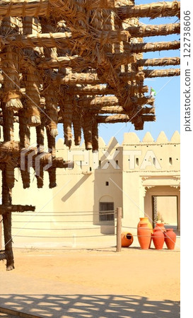 raditional desert architecture exudes rustic charm with pottery in foreground and traditional Arabic design building in background. Cultural heritage shines in harmonious scene raditional desert architecture exudes rustic charm with pottery in foreground and traditional Arabic design building in background. Cultural heritage shines in harmonious scene 122738606