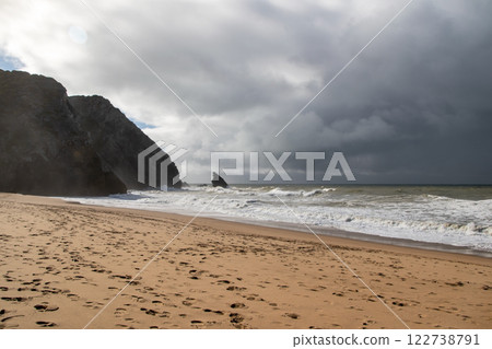 Empty wild sandy beach, Atlantic Ocean seascape, sea waves, beautiful cloudscape, dramatic landscape, travel content, Lisbon, Portugal 122738791