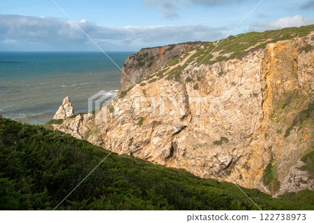 Panorama of the ocean coast and rock bay, Atlantic Ocean in winter, stormy sea waves with white lambs roll ashore with sheer rocks, beautiful cloudscape, dramatic landscape, gloomy seascape 122738973