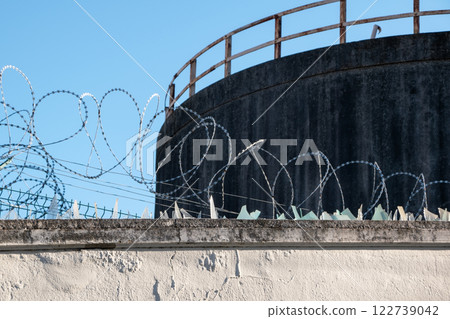 Barbed wire and broken glass keep birds away, security fence 122739042