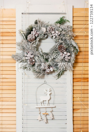 Christmas wreath on wood panel. New Year round decoration with wooden deer pendant 122739134