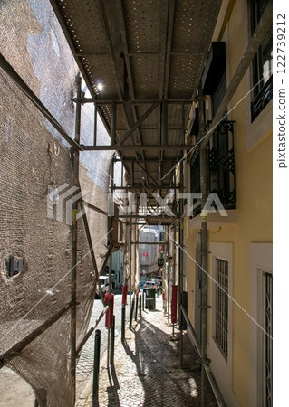 Reconstruction of facade of a historic apartment building on a city street, facade construction mesh covers an old house closed for renovation wall exterior 122739212