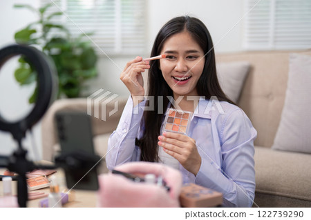 Beauty broker applying eyeshadow with a brush while showcasing her palette in a live broadcast 122739290