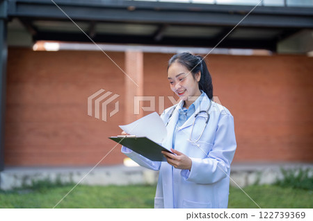 Engaged doctor reviewing patient files with a clipboard in a healthcare environment. 122739369