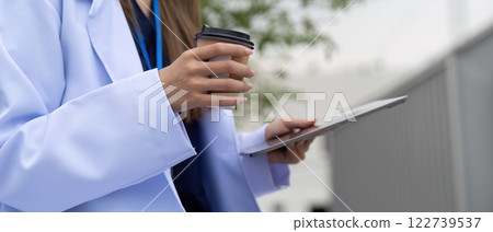 Doctor balancing coffee and tablet for efficient patient care 122739537