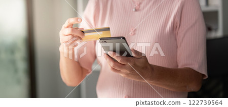 Elderly woman using smartphone to shop online with a credit card. Elderly woman using smartphone to shop online with a credit card. 122739564