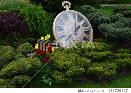 Kharkov, Ukraine, 14 May 2024. A large decorative pocket watch resting among bushes. Timeless Pocket Watch in Enchanted Garden 122739857