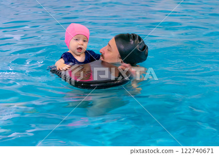Dad and child are swimming indoor pool. Father teachs to swim. 122740671