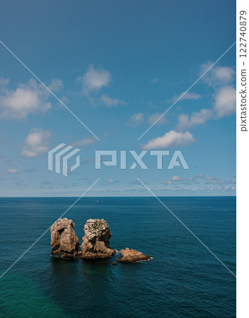 A serene ocean view with a pair of rugged rock formations rising from the deep blue water 122740879