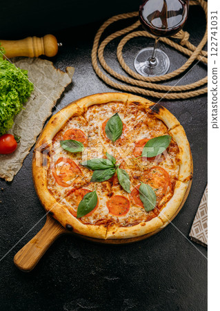 Classic Margherita pizza with fresh basil, tomatoes, and mozzarella on a wooden board 122741031