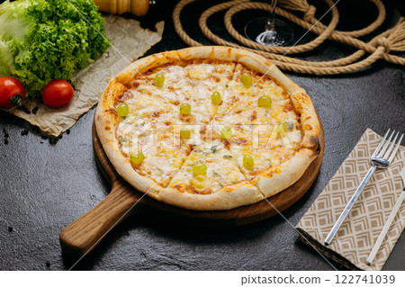 Gourmet four-cheese pizza with green grapes, served on wooden board in a stylish restaurant setting 122741039