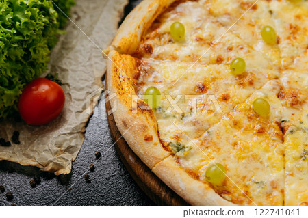 Gourmet four-cheese pizza with green grapes, served on wooden board in a stylish restaurant setting Gourmet four-cheese pizza with green grapes, served on wooden board in a stylish restaurant setting 122741041