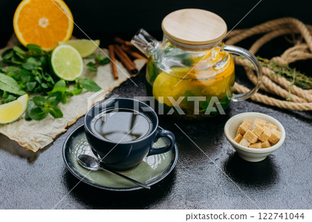 Herbal citrus tea with fresh mint, lime, orange and brown sugar served in a glass teapot and cup 122741044