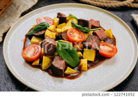Gourmet beef cubes with roasted potatoes, cherry tomatoes and spinach with rich sauce and wine Gourmet beef cubes with roasted potatoes, cherry tomatoes and spinach with rich sauce and wine 122741052