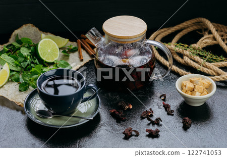 Aromatic herbal tea with cinnamon, mint, lime, and hibiscus in a stylish teapot and cup setting Aromatic herbal tea with cinnamon, mint, lime, and hibiscus in a stylish teapot and cup setting 122741053