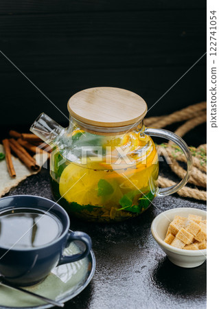 Herbal citrus tea with fresh mint, lime, orange and brown sugar served in a glass teapot and cup Herbal citrus tea with fresh mint, lime, orange and brown sugar served in a glass teapot and cup 122741054