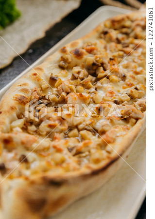 Turkish pide with diced chicken, cheese, and vegetables on plate in traditional gourmet presentation 122741061