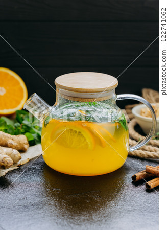Glass teapot with citrus and ginger herbal tea, infused with fresh mint and cinnamon Glass teapot with citrus and ginger herbal tea, infused with fresh mint and cinnamon 122741062