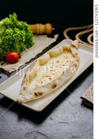 Turkish cheese pide with melted mozzarella on a plate in elegant and traditional food presentation 122741063