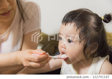 [Baby with tied hair eating baby food] 122741187
